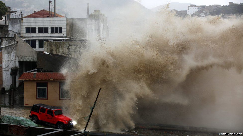 A huge wave crashes along a shore as typhoon approaches