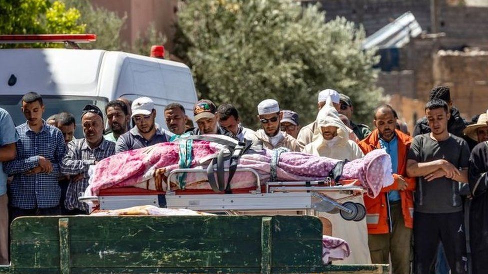 People recite a prayer in front of the bodies of victims killed in an earthquake in Moulay Brahim, Al Haouz province