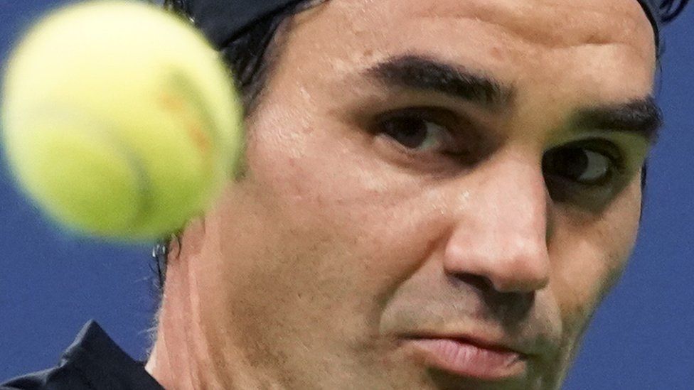 A close-up of Roger Federer's face during a tennis match, while he looks a tennis ball.