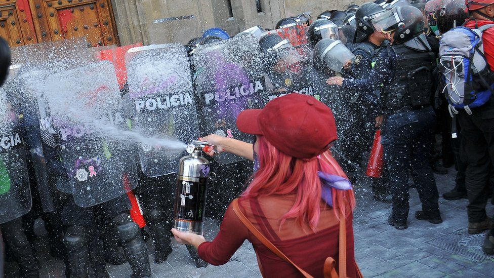 A woman faces the police while taking part in a protest during the International Women's Day in Mexico City