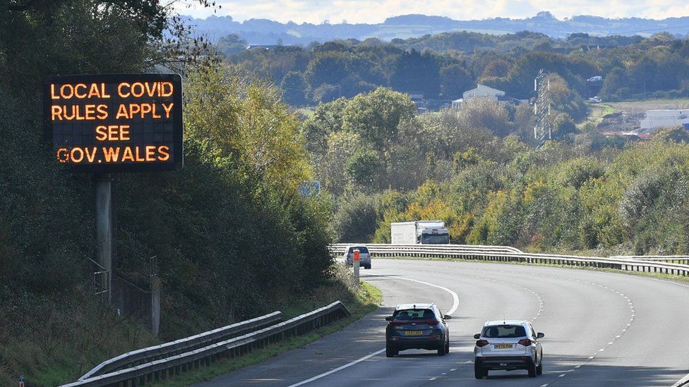 File image of cars driving past a sign advertising Welsh Covid restrictions