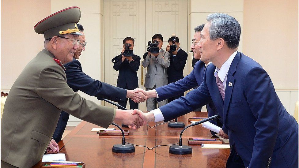 South Korean presidential security adviser Kim Kwan-Jin (right), shakes hands with Hwang Pyong-So (left), North Korea' top political officer for the Korean People's Army. Both are accompanied by another official each, and media.