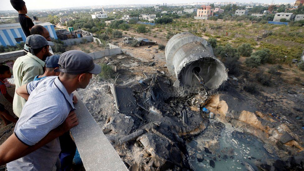 Palestinians look at damage at the site of an Israeli air strike on the outskirts of Gaza City (9 August 2018)