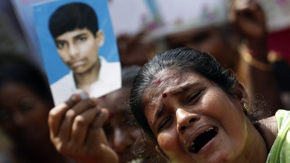 A Tamil woman holds up an image of her disappeared family member during the war against Liberation Tigers of Tamil Eelam (LTTE), at a protest in Jaffna (27 August 2013)