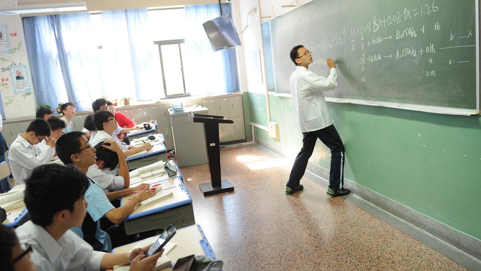 Chinese student completing maths problem on the board at the front of the class