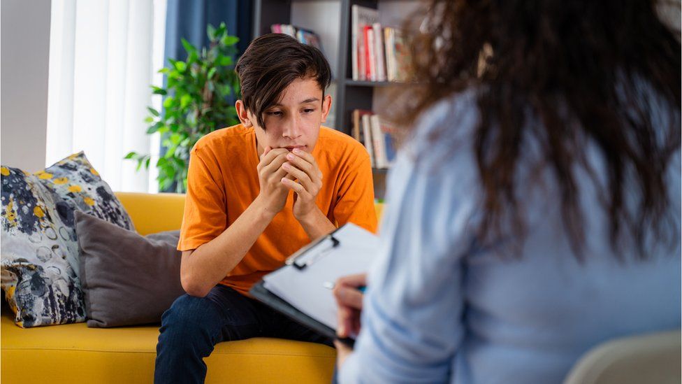 Female psychologist counseling teenage boy in office - stock photo