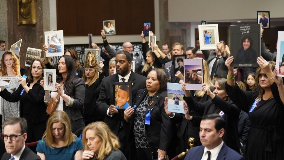 Families of victims holding up photos of their loved ones