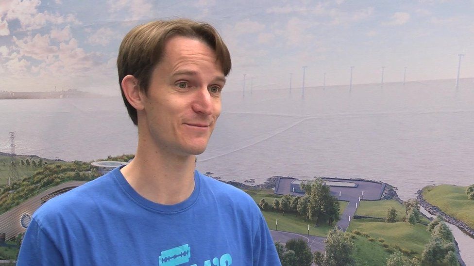 A man in a blue shirt and short brown hair