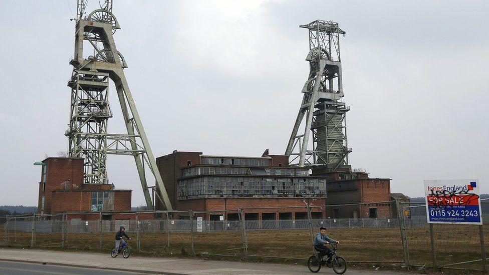Boys cycle past the closed Clipstone Colliery in Clipstone near Mansfield