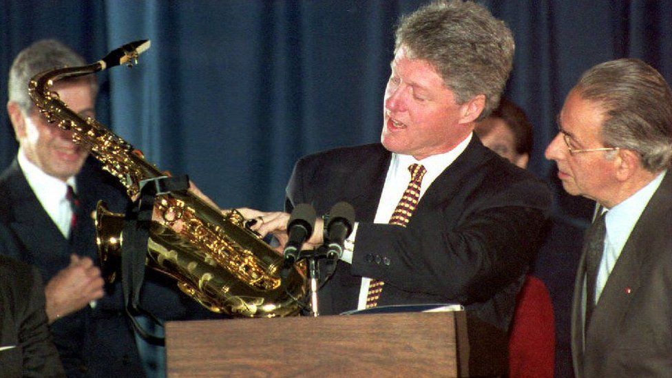 President Bill Clinton accepts a gift of a saxophone at a reception at the Conrad Hotel 09 January 1994 from a delegation of the Belgian town of Dinant, Belgium.