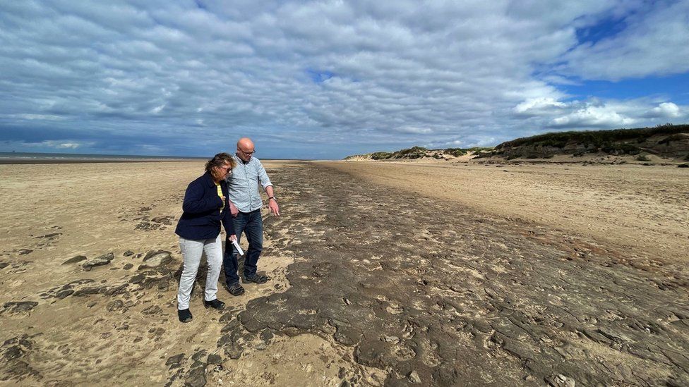 Alison Burns and Jamie Woodard examine a bed of ancient footprints at Formby