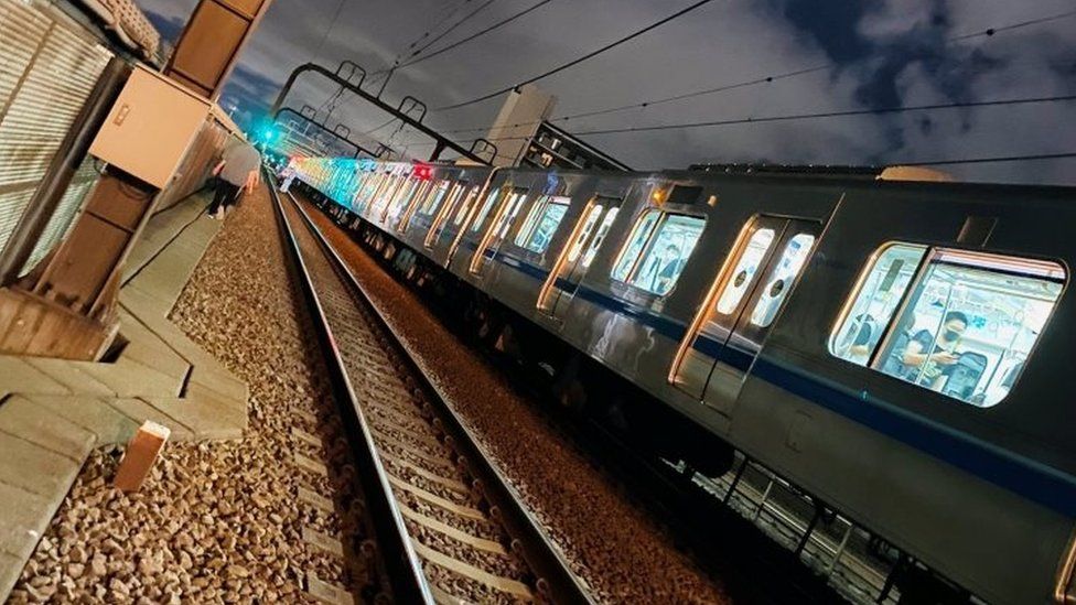 Люди идут по железнодорожным путям после ножевого нападения на поезд в Токио
