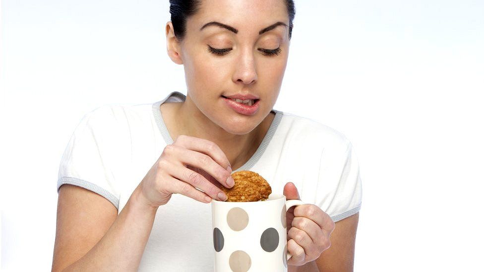 Woman dips biscuit in tea