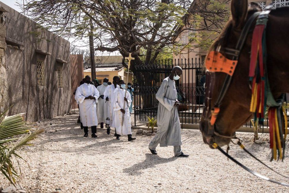 An altar boy carries a cross at the start of Easter Mass in Fadiouth, Senegal.
