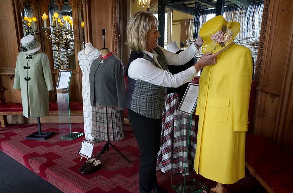 Assistant curator Sarah Hoare adjusts outfits worn by Queen Elizabeth II whilst at Balmoral as they go on display in the Castle Ballroom at the opening of Life at Balmora