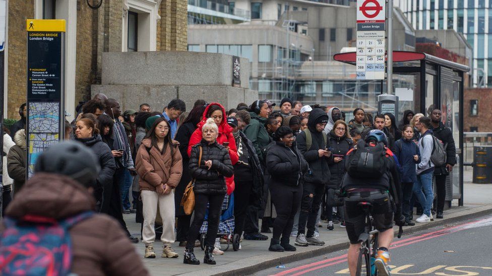People queue for a bus at London Bridge