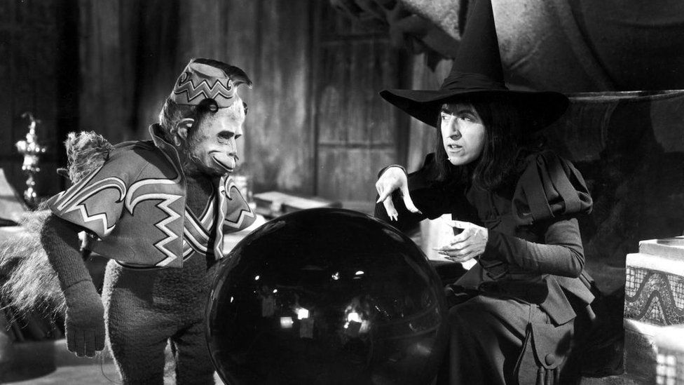 Margaret Hamilton (1902 - 1985) and a winged monkey look into a crystal ball in a still from the film, 'The Wizard of Oz,', 1939