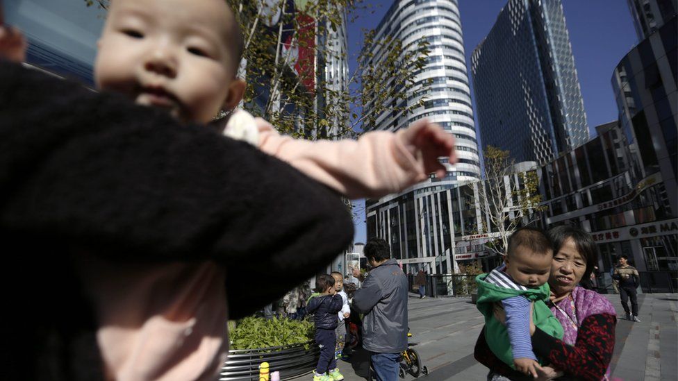 Chinese women carry their babies in a shopping district in Beijing on 30 October 2015
