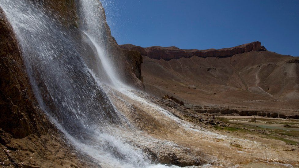 A waterfall created by natural "travertine" dams contrasts the high desert red rock cliffs at Band-E-Amir National Park September 6, 2009 in Band-E-Amir, Afghanistan.