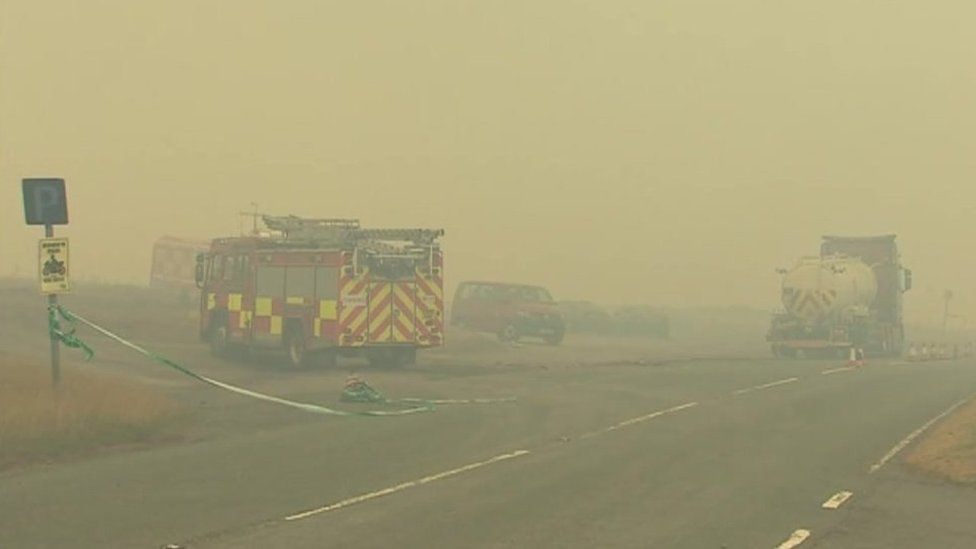 Fire engine shrouded in smoke at roadside