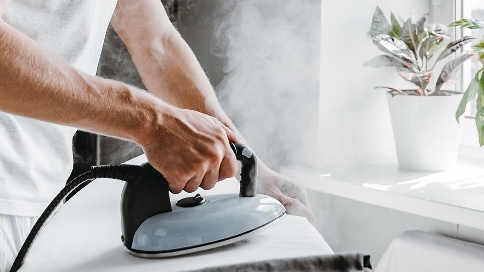 Person using steam iron in home