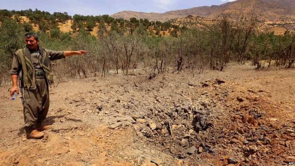 A PKK fighter inspects a crater reportedly caused by a Turkish air strike in the Qandil mountain 29.07.2015
