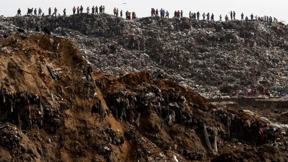 Garbage collectors look at rescue teams working at the site where a massive pile of garbage collapsed at a landfill dumpsite in Guatemala City