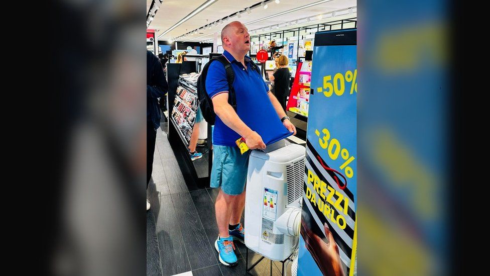 Mark Regan stands at an air conditioner