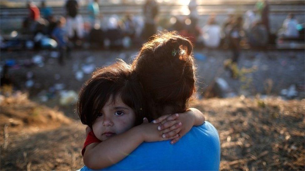 A young Syrian migrant girl is held by her mother