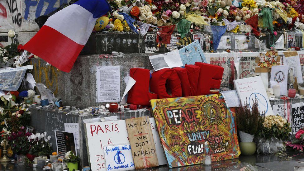 French national flags, candles and flowers at a makeshift memorial in Place de la Republique square