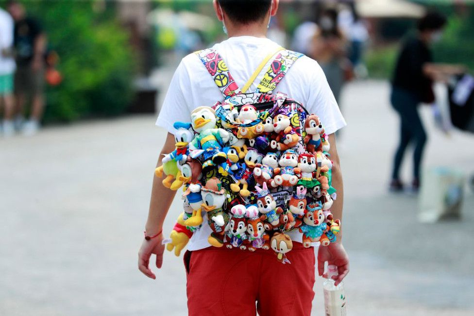 A visitor walks with dolls hanging from the backpack