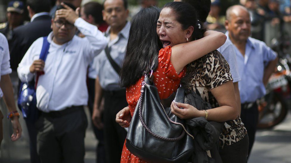 Two women embrace as one cries on the street in Mexico City