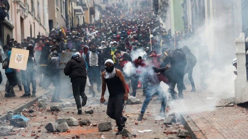 A road full of protesters armed with shields and holding wooden sticks