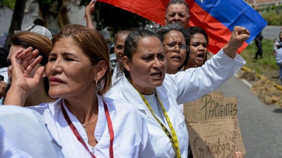 Health workers shout slogans demanding fair and higher wages during a protest for the lack of medicines, medical supplies and poor conditions in hospitals, in front of the headquarters of the Episcopal Conference in Caracas, on July 25, 2018.