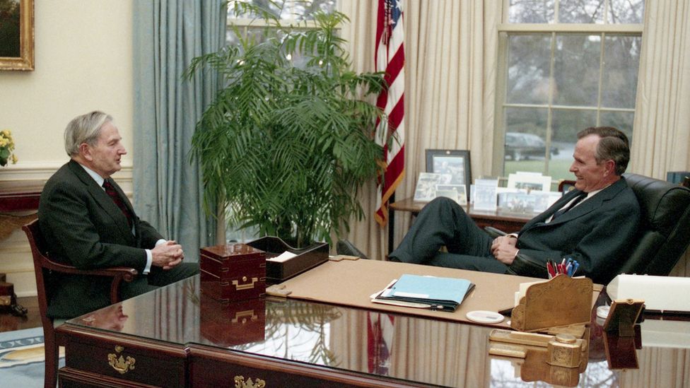 Former President George HW Bush (R) and David Rockefeller speak in the Oval Office at the White House in this undated photo.