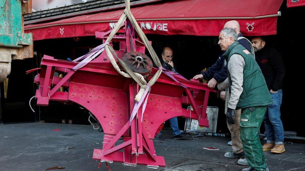 The broken sails of the landmark red windmill atop the Moulin Rouge, Paris' most famous cabaret club, are taken away after they fell off during the night in Paris,