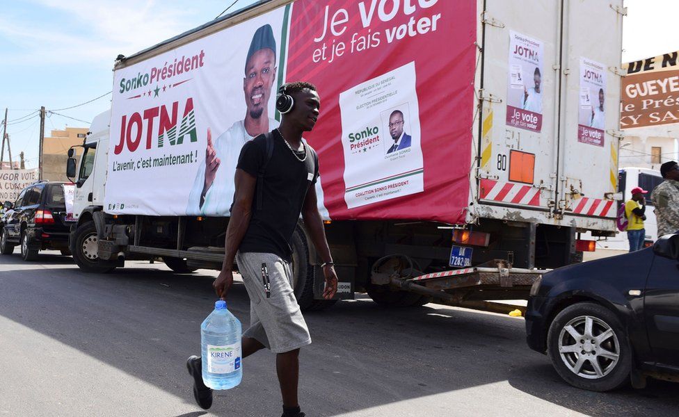 A man walks past a truck with a poster of presidential candidate Ousmane Sonko on 3 February 2019, Dakar, Senegal