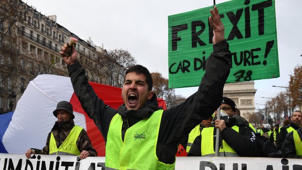 A demonstrator gestures in front of placards
