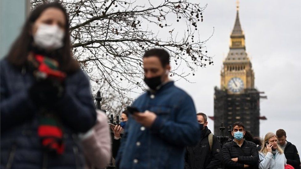 People queueing for a coronavirus vaccination, with Parliament in the background