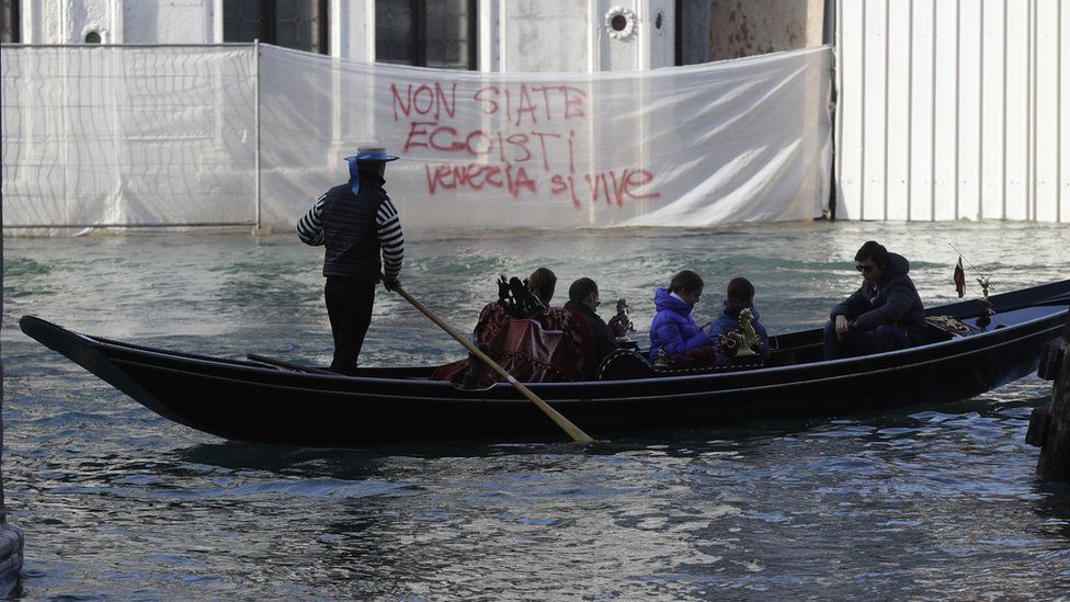 A gondola sails past a writing reading "Don"t be selfish, Venice is to be lived" during a protest against the increasing number of tourists in Venice, Italy, Saturday, Nov.12. 2016