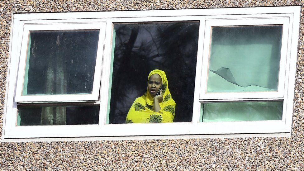 A woman seen in a window on a mobile phone