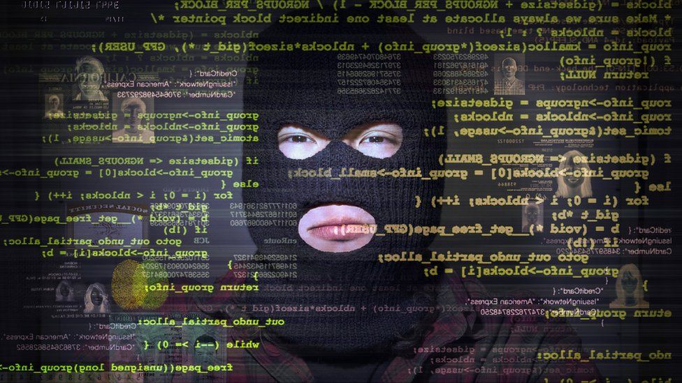 Man in balaclava surrounded by computer code