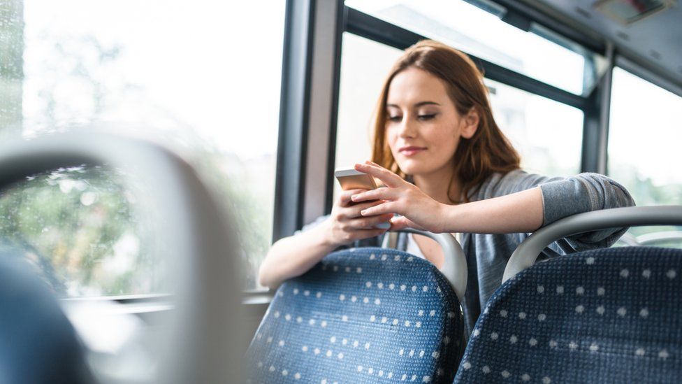 A woman looking at her mobile phone while on a London bus