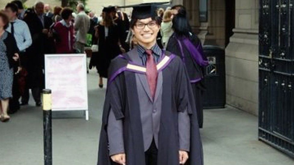 Reynhard Sinaga posing for a picture in his graduation gown
