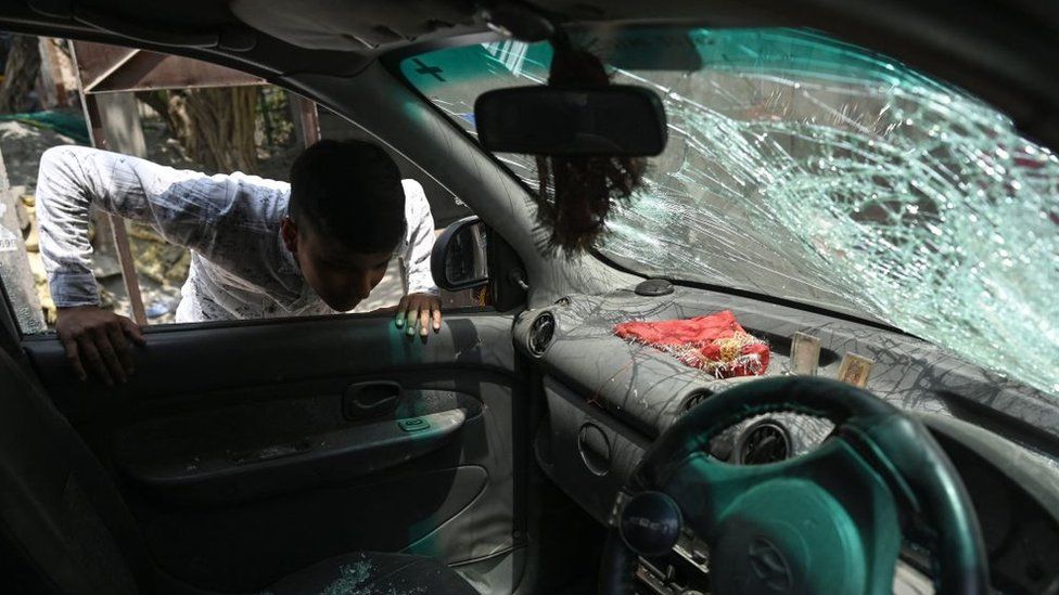 Молодой человек заглядывает в поврежденный автомобиль в жилом районе Джахангирпури в Нью-Дели 17 апреля 2022 года после столкновений между членами двух общин 16 апреля во время религиозной процессии «Хануман Джаянти».