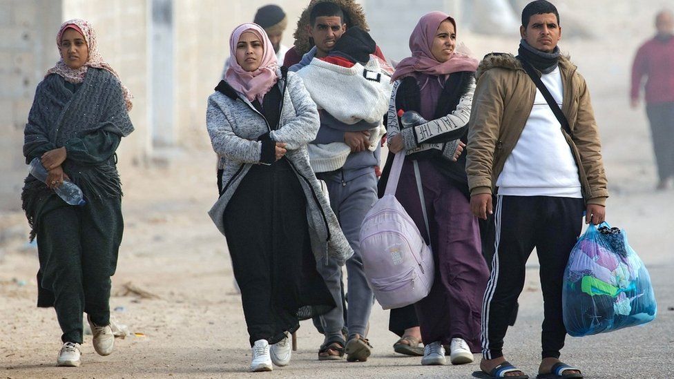 Displaced Palestinians walk along the coastal road after the Israeli military told residents of western Khan Younis to flee (23 January 2024)