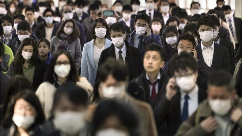 Office workers wearing protective masks to avoid infection from the coronavirus walk to their offices after taking overcrowded commuter trains, at a railway station in central Tokyo, Japan, 06 April 2020.