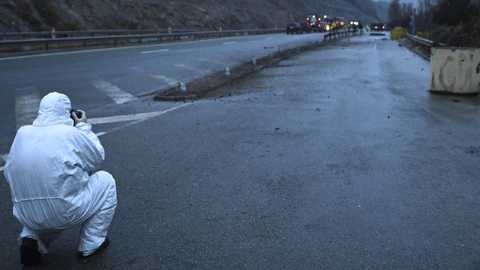 Tyrėjas nufotografuoja greitkelyje užsiliepsnusio autobuso su Šiaurės Makedonijos numeriais nuolaužas