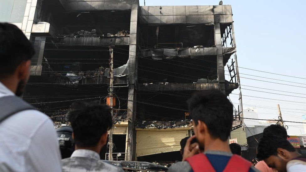 Onlookers outside the burnt building in Delhi on 14 May