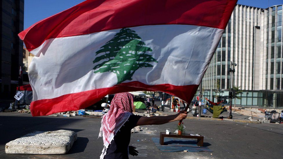 An anti-government protester holds up a Lebanese flag at a camp in Beirut (30 October 2019)
